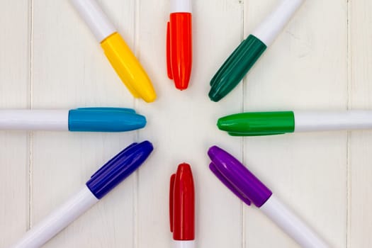 Multi-colored markers on a white wooden background. Top view. Copy space