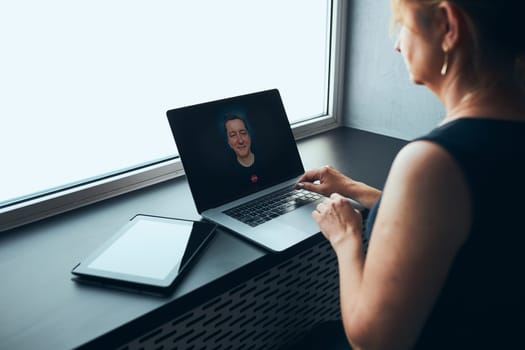 Businesswoman having business video call on laptop in office. Mature busy woman remotely working from office. Female manager using digital devices. Remote communication. Video calling. Remote work