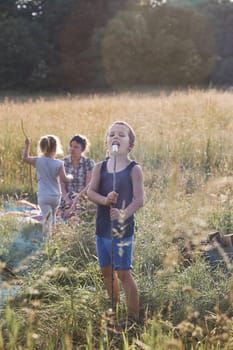 Boy eating a marshmallow after roasting it over a campfire on a meadow. Candid people, real moments, authentic situations