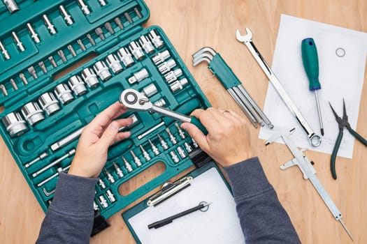 Man working in workshop using many tools. Wrench, spanner, calliper and ratchet with many attachments. Work tools. Universal tool set. Professional equipment