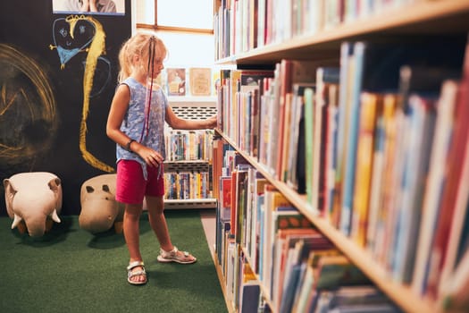 Schoolgirl looking for book for reading in school library. Student choosing literature for reading. Books on shelves in bookstore. Learning from books. Back to school. Elementary education. Doing homework