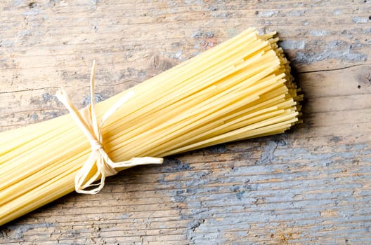 Italian raw pasta on rustic wooden table from above. Traditional long spaghetti dry. Top view.