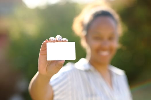 Black woman showing credit card mock up in a park