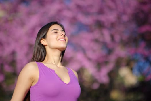 Happy woman breathing fresh air standing in a violet park