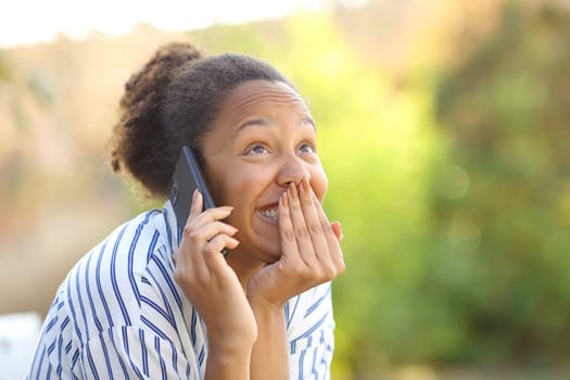 Funny black woman calling on phone in a park