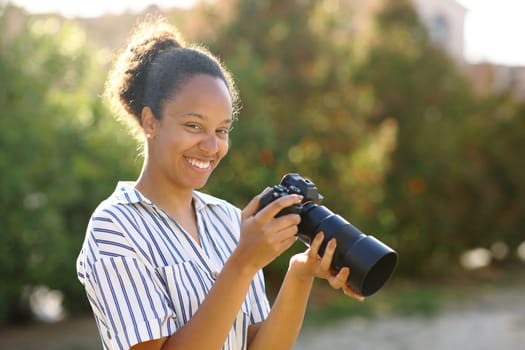 Happy black photographer posing looking at camera in a park