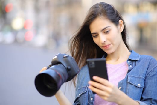 Photographer using phone holding camera in the street