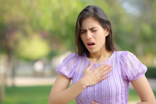 Stressed woman suffering asthma attack in a park