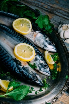 Fresh mackerel fish with lemon and spices served on silver plate from above. Homemade seafood dish recipe cooking. Healthy diet food prepared for dinner.