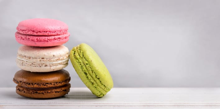 Retro pastel colorful macaroon cookies on vintage background with copyspace. Homemade french macaron dessert with different flavors: chocolate, strawberry, vanilla, pistachio. Candy shop sweet menu design.