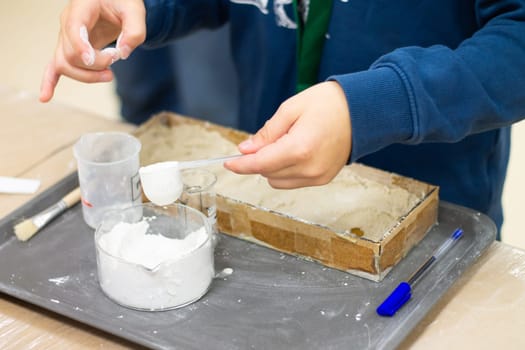 Child's hands are preparing a plaster mix in the laboratory for research