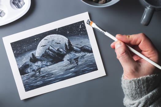 Hand drawing moon and mountains in black and white with brush on gray background, monochrome flat lay