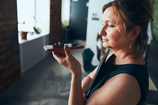 Woman having business call working in office. Mature woman talking on mobile phone using speaker mode. Using technology. Remote communication. Remote work