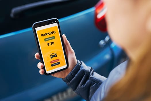 Woman using mobile parking app on smartphone. Driver using smartphone to pay for parking. Car park application on mobile phone. Convienience paying for parking using fast payment online. Mobile park service