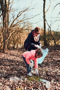 Family cleaning up a forest. Volunteers picking plastic waste to bags. Concept of plastic pollution and too many plastic waste. Environmental issue. Environmental damage. Responsibilitiy for environment. Real people, authentic situations