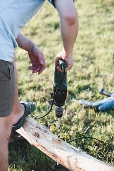 Man drilling hole in timber while working in garden