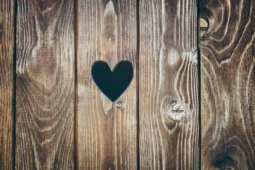 Wooden door with heart shape hole. Wood texture background. Old rustic plank surface