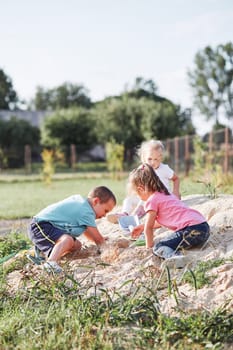 Children, little girls and boy, playing in sandbox in playground outside on summer day. Real people, authentic situations