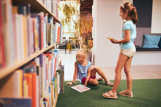 Schoolgirls looking for book for reading in school library. Students choosing books for reading. Learning from books. Back to school. Elementary education. Doing homework