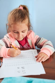 Little girl preschooler learning to write letters at school. Kid writing letters doing a school work. Concept of early education