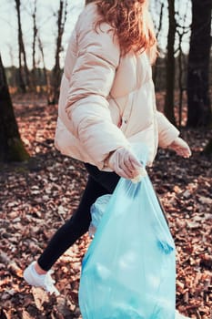 Young woman cleaning up a forest. Volunteer picking plastic waste to bags. Concept of plastic pollution and too many plastic waste. Environmental issue. Environmental damage. Responsibilitiy for environment. Real people, authentic situations