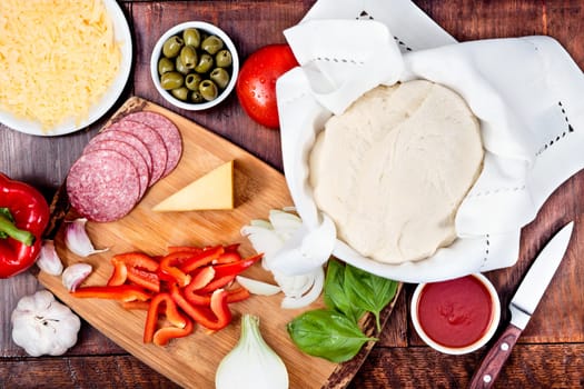 Ingredients, cheese, vegetables prepared for homemade pizza, on wooden board on the table. View from above