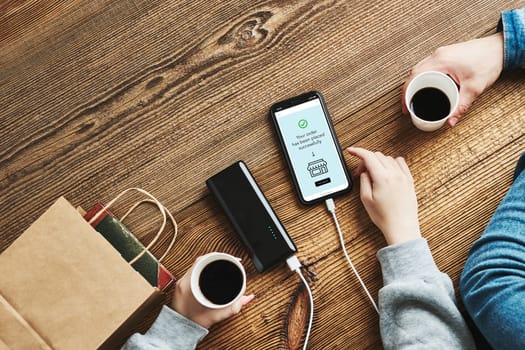 Online shopping. Paying online. Ordering product in online shop using smartphone. Payment confirmation on screen. Online banking. Paying for online shopping while charging mobile phone from powerbank in coffee shop