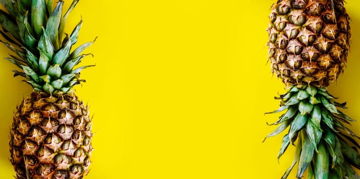 Top view of pineapple border on bright yellow background. Trendy summer smoothie tropical design. Flat lay. Vivid pastel layout with ananas frame from above. Creative food and drink menu.