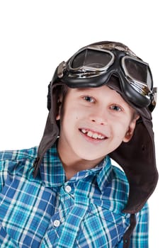 Frontal head and shoulders view of a Caucasian 10 year old boy wearing an attached leather cap and traditional motorcycle goggles against a white background looking happily at the camera.