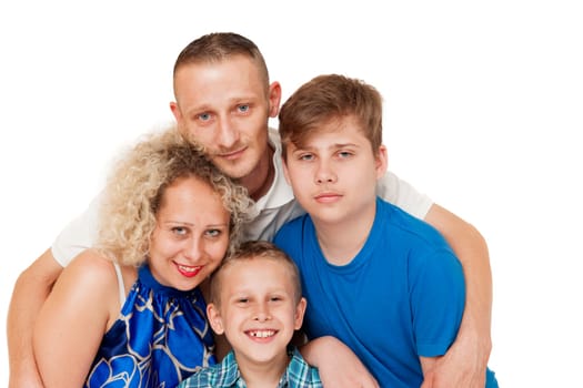 Frontal head-and-shoulders portraits of a young Caucasian family. Father standing behind, smiling, hugging his wife and their sons against a white background.