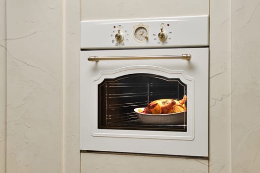 Process of baking food in oven. Whole chicken in ceramic casserole inside the oven.