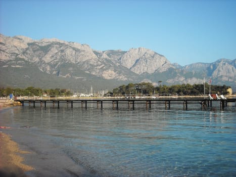 Kemer Antalia nice view of the sea. Beach Kemer Antalia with sand and mountains, the sea with the ship. Beautiful harbor near the sandy beach.