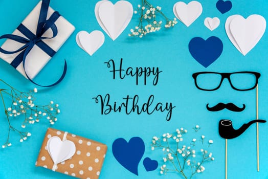 Flat Lay With English Text Happy Birthday. Blue Accessories Like Presents, Hearts, Flowers And Male Decoration Like Mustache. Flat Lay With Turquoise Paper Background.