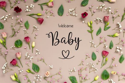 Flower Arrangement With English Text Welcome Baby. Colorful Spring Blossoms And Flowers Like Roses Building A Frame. Flat Lay With Brown Paper Background