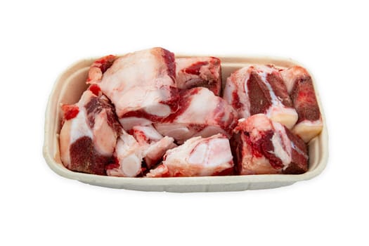 Raw beef bones for soup or sauce on a paper plate isolated over white background