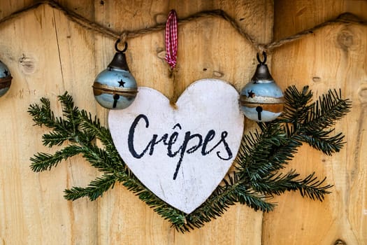 Sweet crepes - flat pancake - sign made of wood in the shape of a heart, hanging on bakery shop.