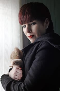 A young woman crying with a teddy bear in her arms