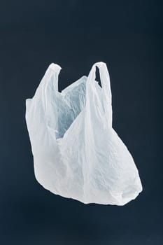 White empty plastic bag floating over black background. Collecting plastic waste to recycling. Concept of plastic pollution and too many plastic waste. Copy space at the top