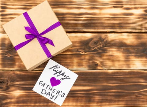 Greeting card Happy Father's Day with a gift box on a rustic wooden tabletop. Flat lay. Top view. Copy space