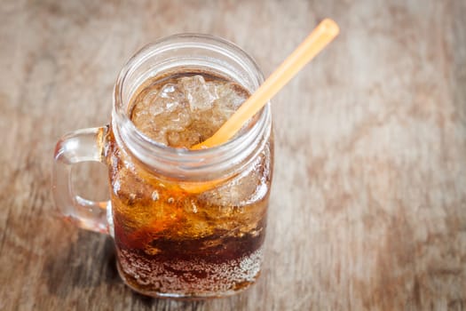 Glass of cola with ice on wooden table, stock photo