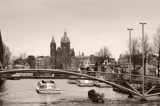 Amsterdam,Netherlands – December 30,2014: Excursion boats in a canal in Amsterdam in front of St. Nicholas Church on 30 December 2014 in Amsterdam.