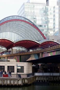 London,United Kingdom – November 29,2014: Pedestrians walk along a promenade under the modern bridge construction of Canary Wharf Tube station in Tower Hamlets,London,November 29,2014.