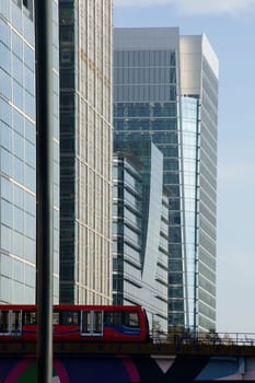 London,United Kingdom – November 29,2014: A red underground railway of the DLR line passes over a colourful bridge to high-rise buildings in the Canary Wharf banking district on 29 November 2014 in London.