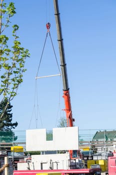 Mobile construction crane wagon on a construction site. Lifts up a concrete finished wall.