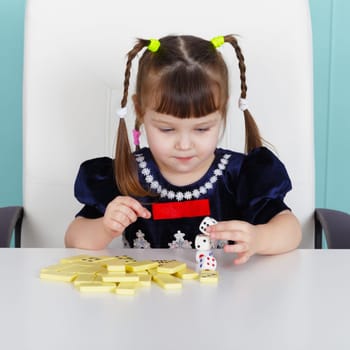 Little girl playing with toys, sitting at the table