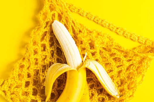 A string bag with bananas isolated on yellow background.