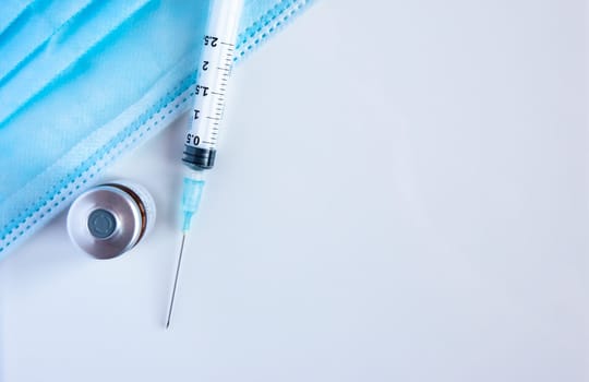 A bottle of vaccine with syringe and surgical masks. Coronavirus vaccine.