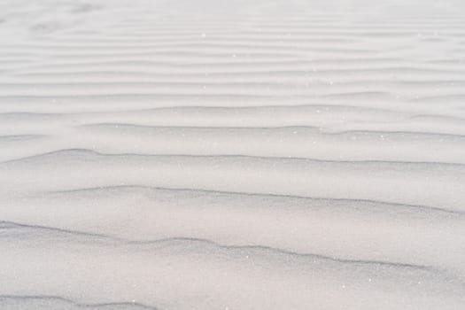Pattern of sea ripples was left by waves on coastal white sand. Sea coast. Tourism and travel. Calm and serenity. Natural background. Natural texture. Dunes. Abstract drawing.