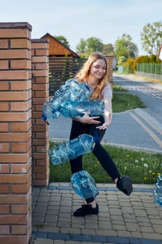 Young woman throwing out empty used plastic water bottles into trash bin. Collecting plastic waste to recycling. Concept of plastic pollution and too many plastic waste. Environmental issue
