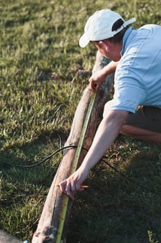 Man using steel tape measure to measuring of timber while working in garden